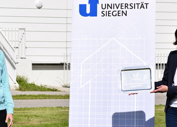 Uni Siegen hält FISU Attribution Plaque in den Händen